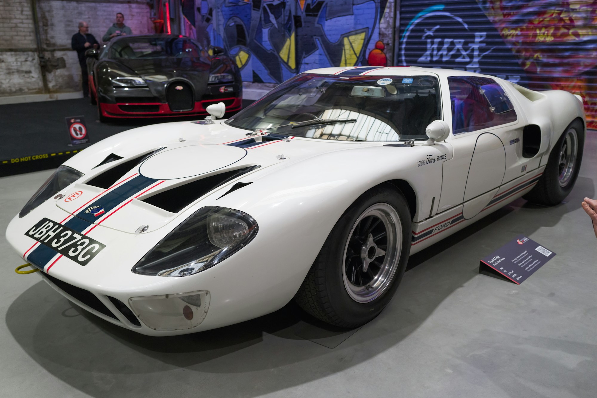A 1960s race-bred coupé under a single spotlight.